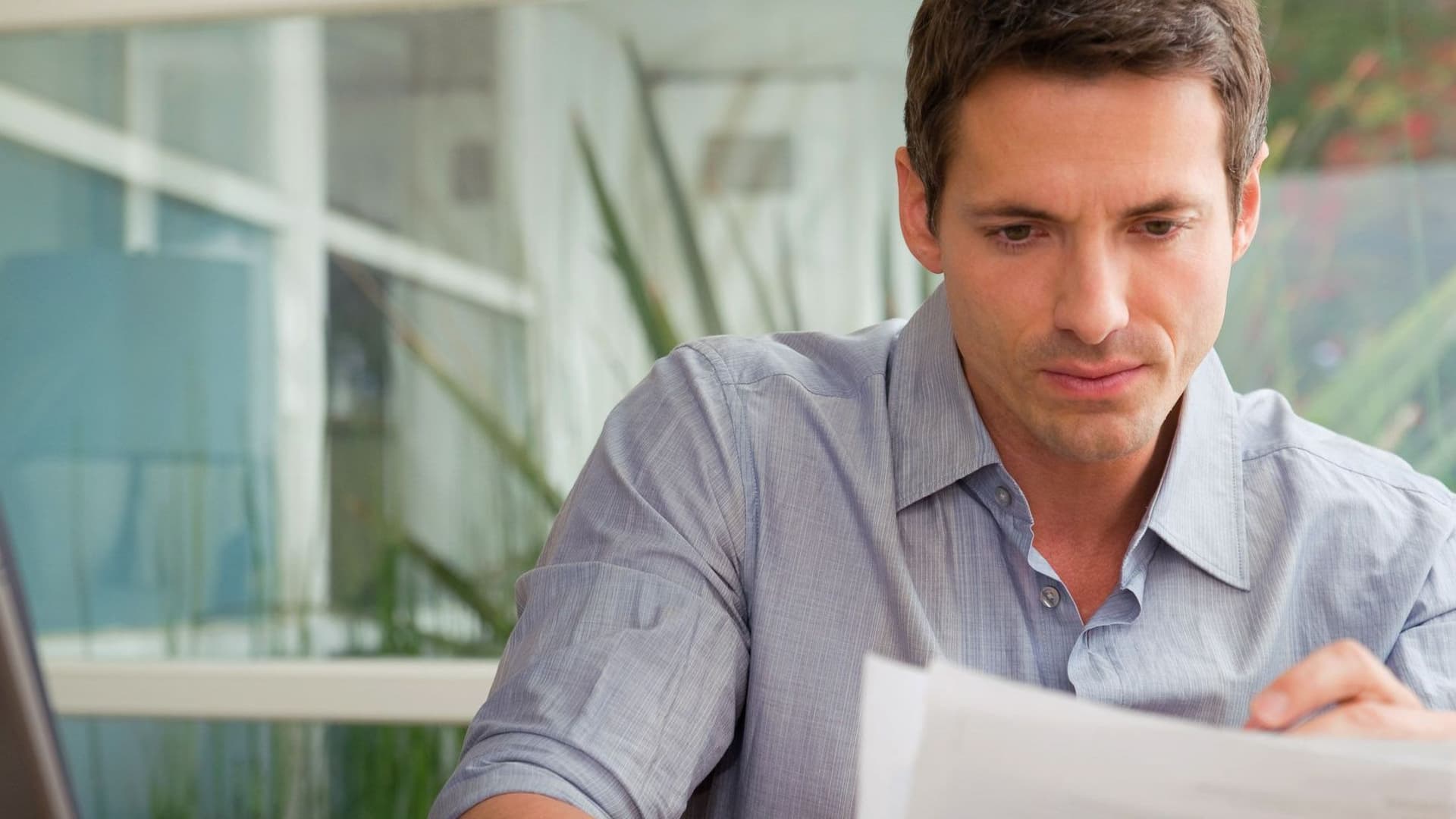 Ein Mann hält Blätter Papier in der Hand und liest.