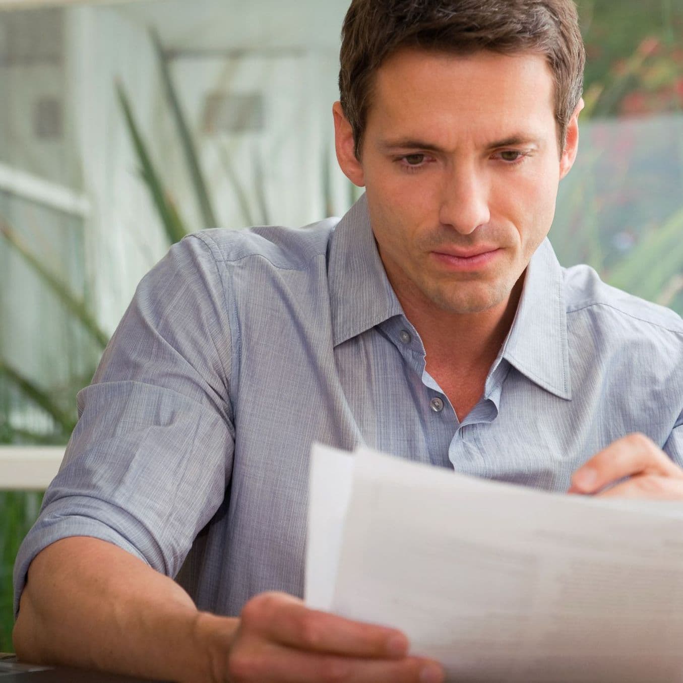 Ein Mann hält Blätter Papier in der Hand und liest.
