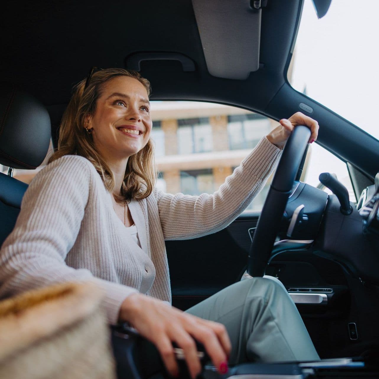 Frau sitzt im Auto und strahlt übers Gesicht.