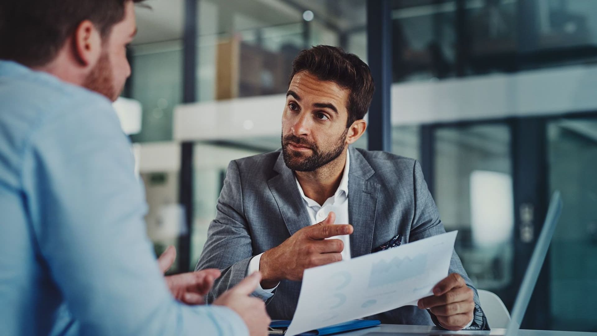 Zwei Männer am Laptop, einer erklärt etwas.