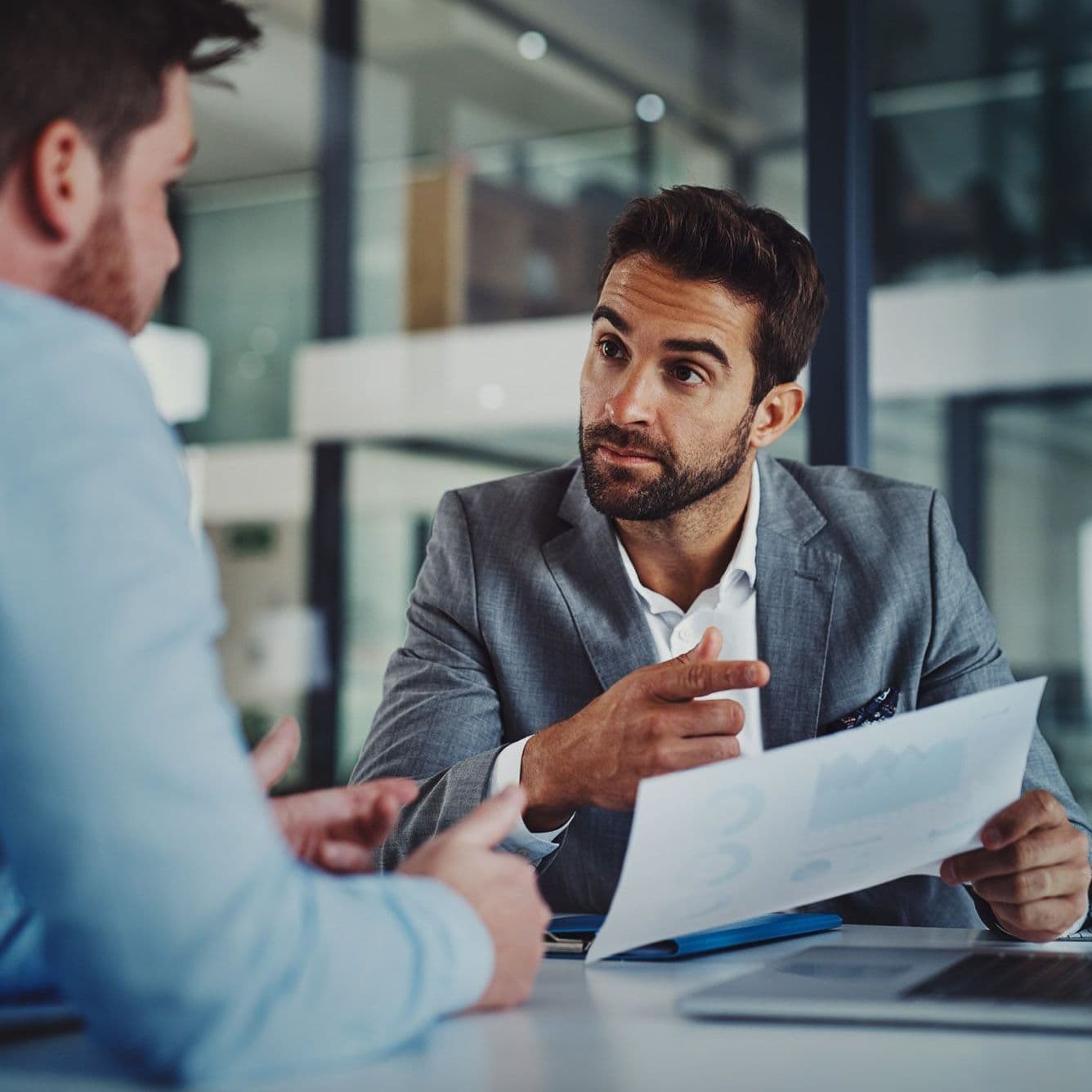 Zwei Männer am Laptop, einer erklärt etwas.