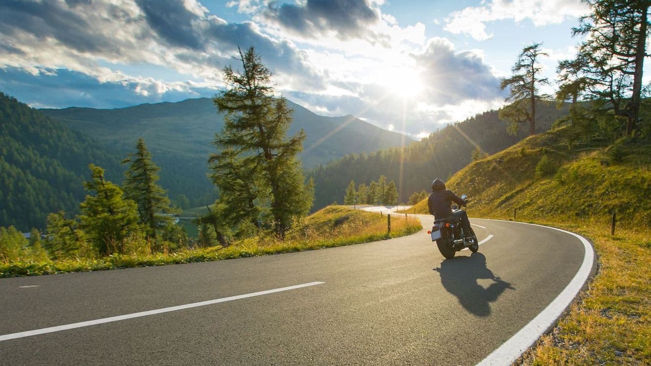 Motorradfahrer fährt in malerischer Umgebung.