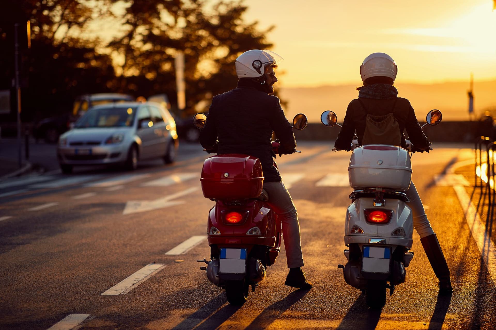 Zwei Rollerfahrer stehen auf der Straße.