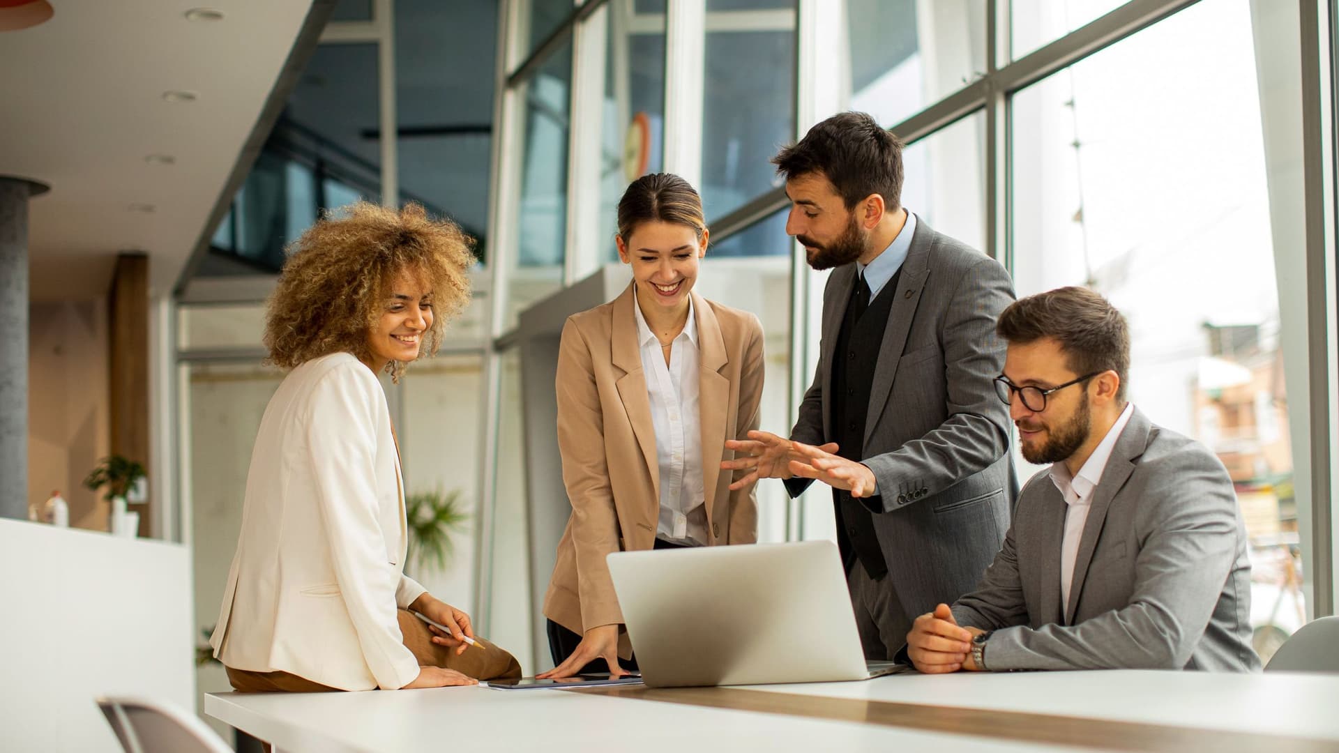 Vier Personen stehen bei der Arbeit lächelnd zusammen.