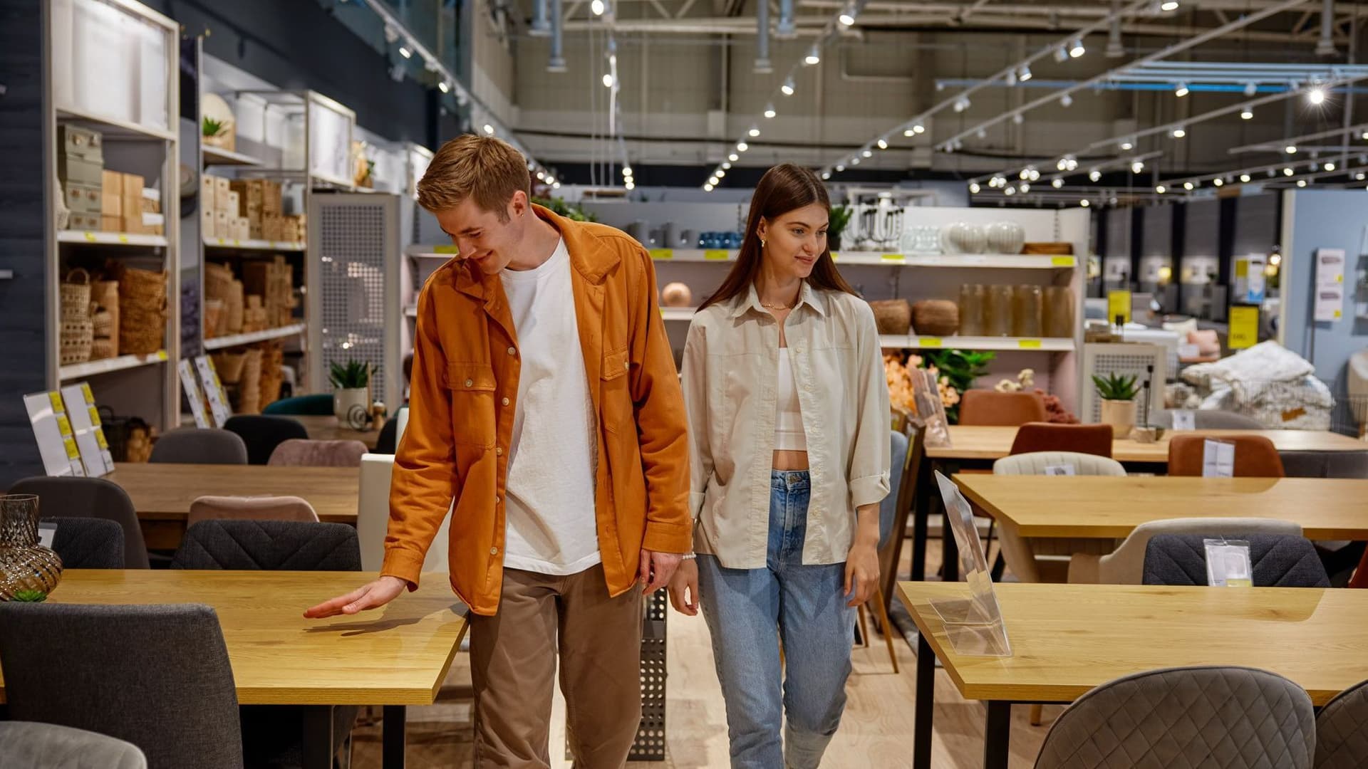 Zwei Junge Leute laufen im Möbelhaus durch die Tischabteilung.