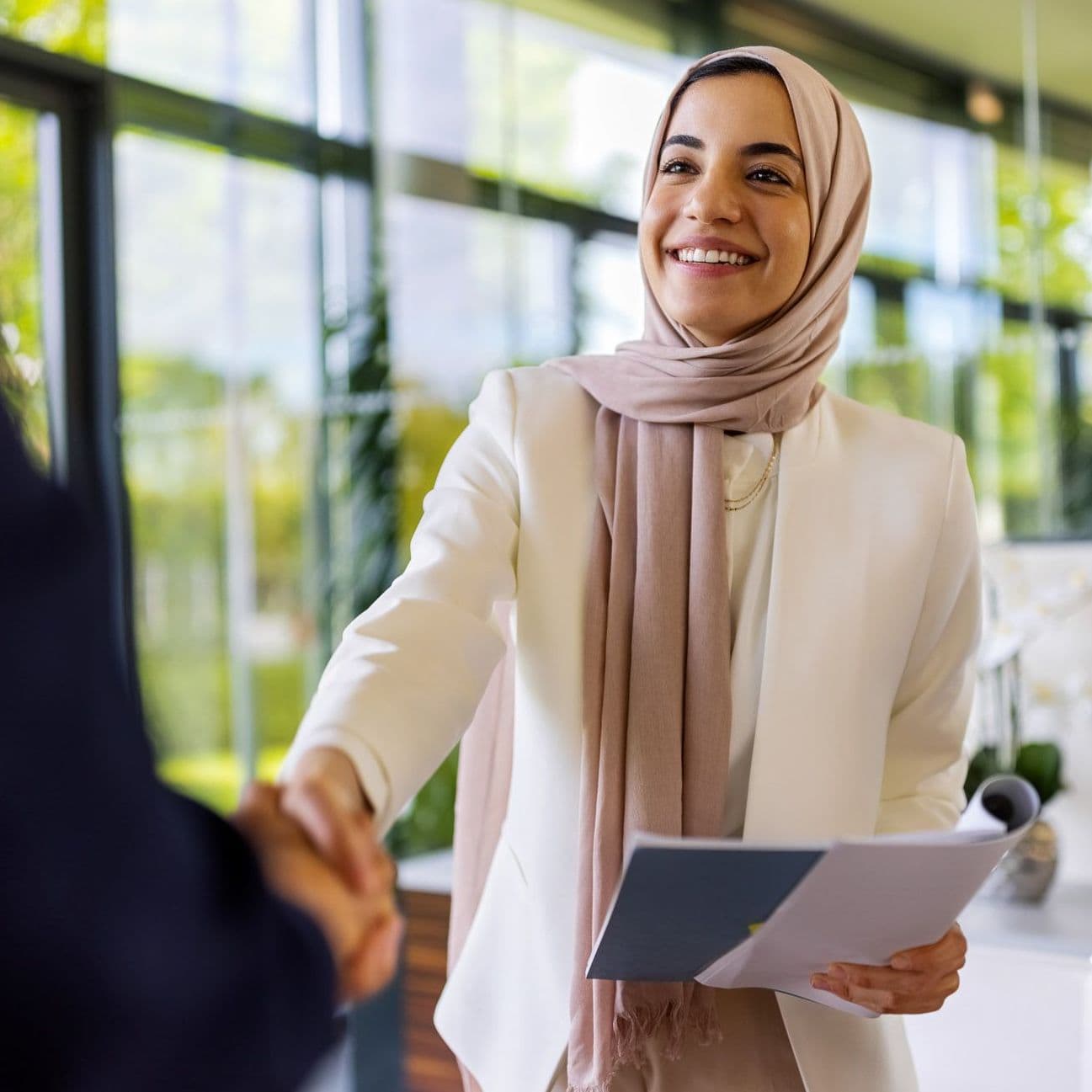 Frau schüttelt einer anderen Person die Hand.