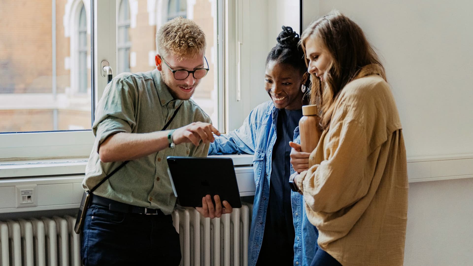 Drei junge Leute blicken auf ein Tablet.
