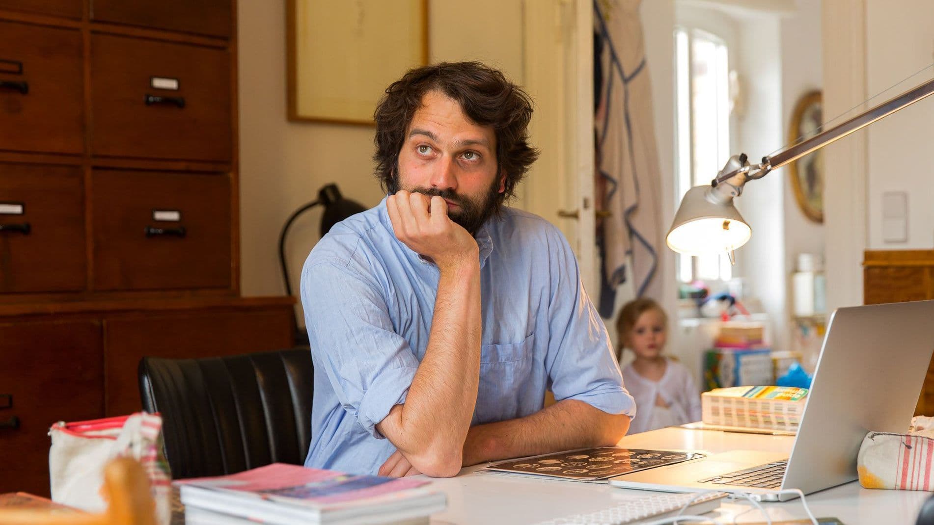 Mann sitzt am Schreibtisch und guckt nachdenklich.