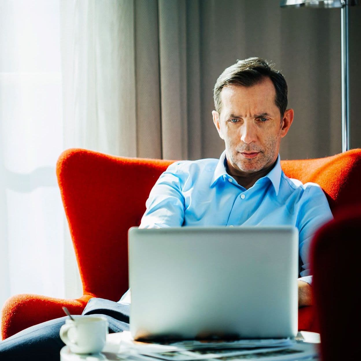 Mann sitzt vor Laptop.