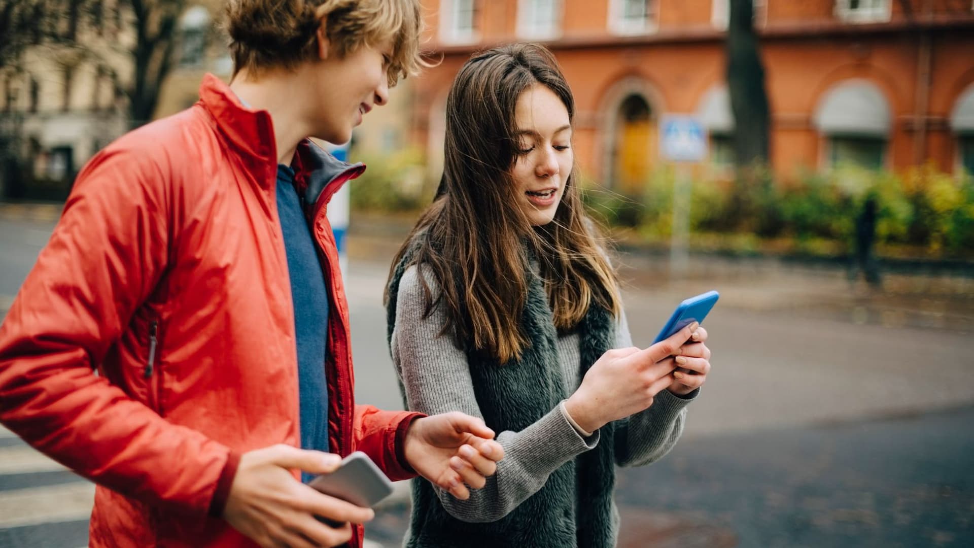 Zwei junge Leute blicken auf ein Handy.