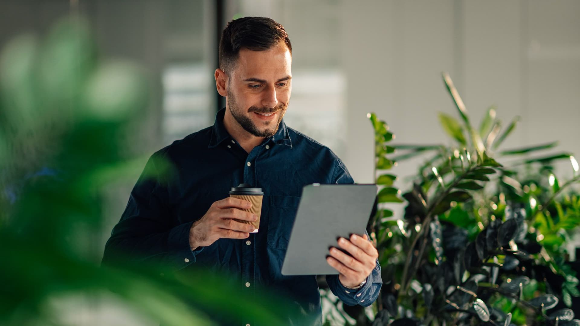 Mann hält Tablet in der Hand und lächelt.