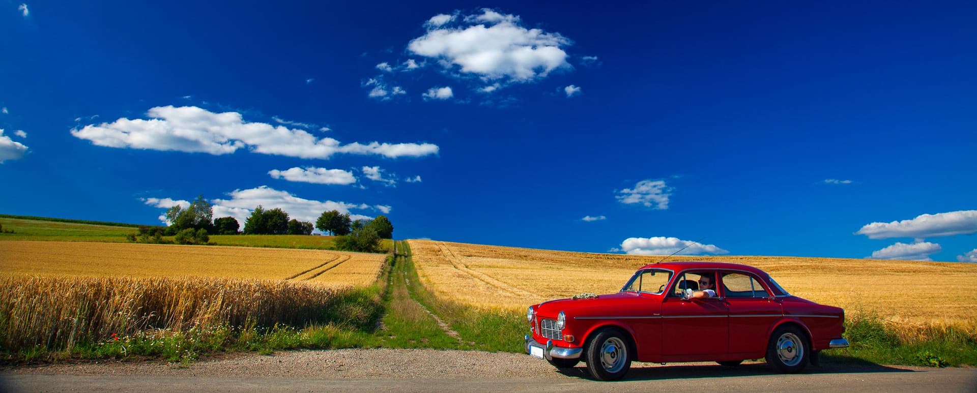 Roter Oldtimer steht am Feldrand.